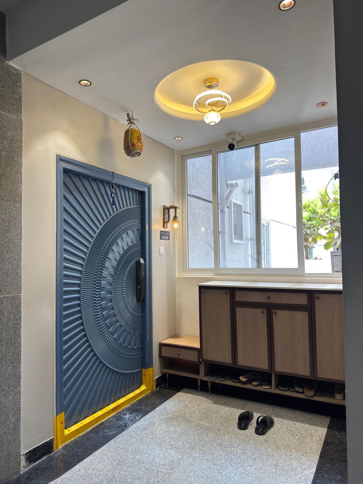 Hand-carved blue entrance door with brass detailing, designed by Nikhila Nayini